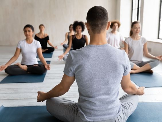 H1 A group of yogis practicing with the teacher's back facing camera